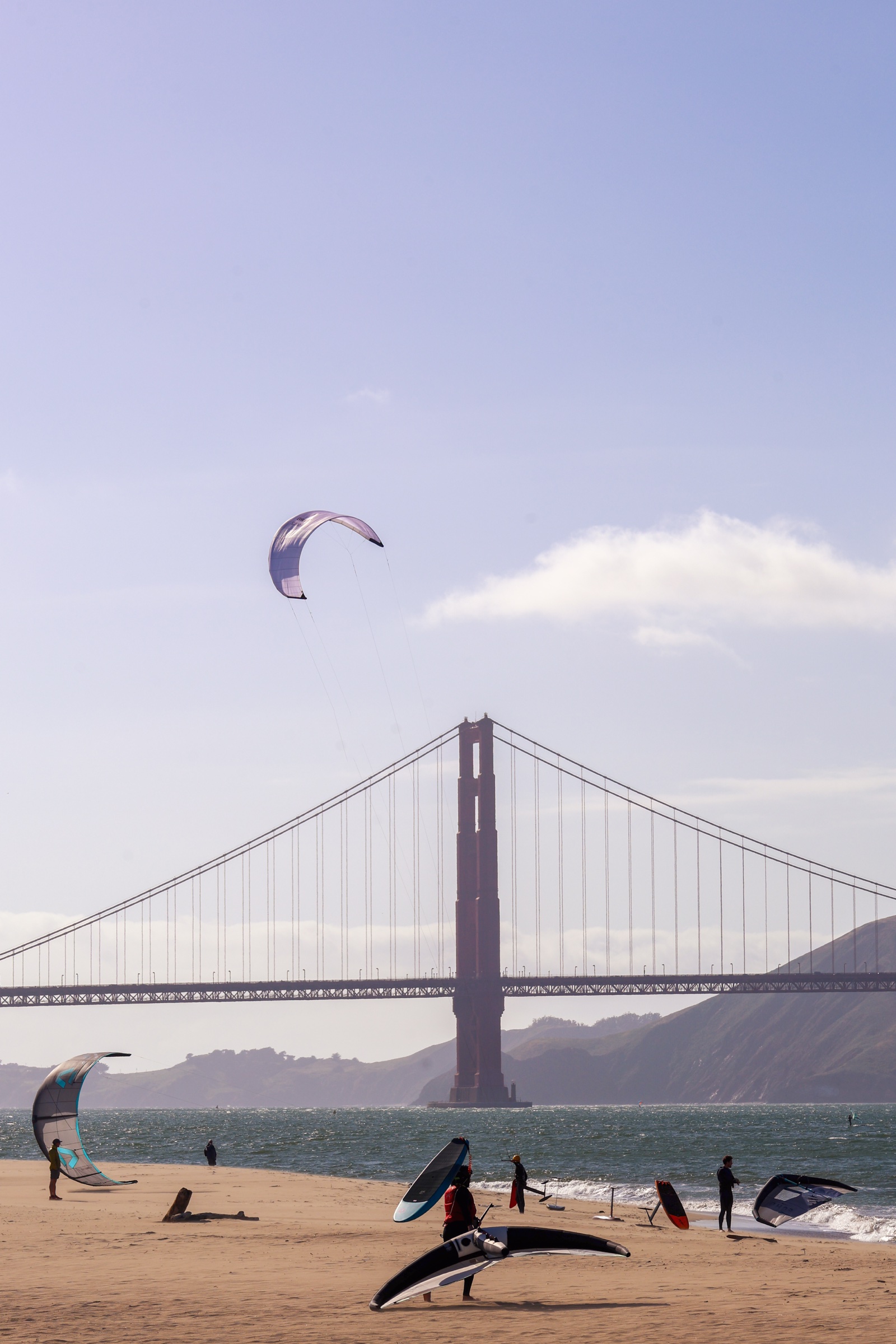 Kite surfers on the sand below the Golden Gate Bridge
