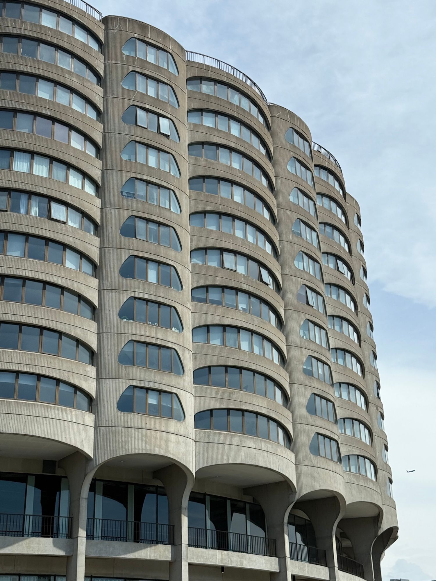 A curved concrete apartment tower stacked with almond-shaped windows